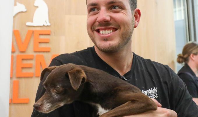 Alex Bowman smiling and holding a small dog